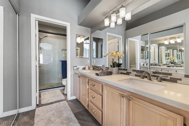 bathroom with toilet, a shower stall, double vanity, and a sink