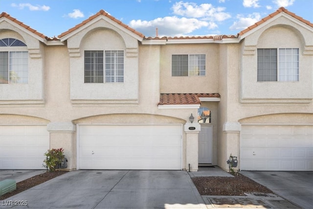 view of property with a garage, driveway, and stucco siding