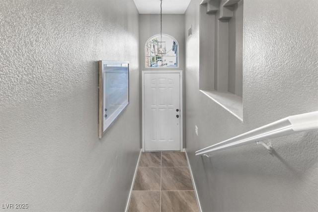 doorway to outside featuring baseboards and a textured wall