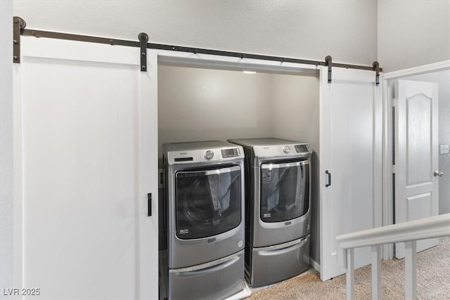 washroom featuring laundry area, a barn door, and washing machine and dryer