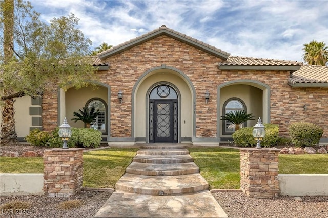 property entrance featuring a tile roof, a yard, and stucco siding