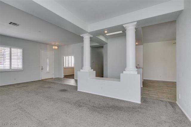 interior space featuring baseboards, visible vents, and ornate columns