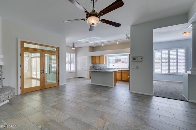 kitchen with a center island, french doors, light countertops, open floor plan, and a sink