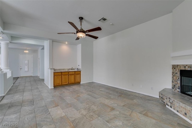 unfurnished living room with decorative columns, a fireplace, visible vents, and baseboards