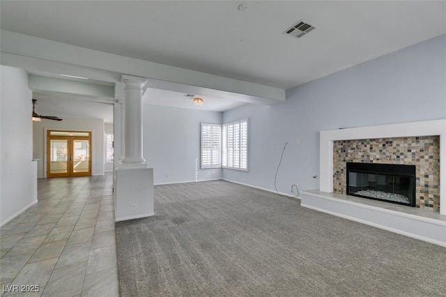 unfurnished living room featuring light carpet, a fireplace, visible vents, baseboards, and decorative columns