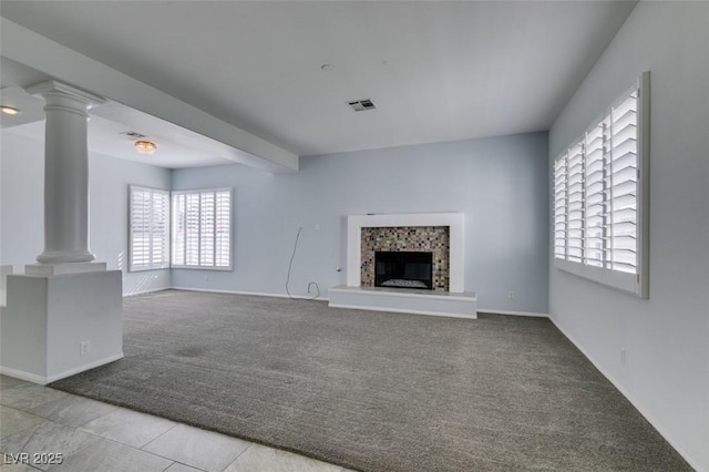 unfurnished living room featuring a fireplace, visible vents, beam ceiling, carpet, and ornate columns