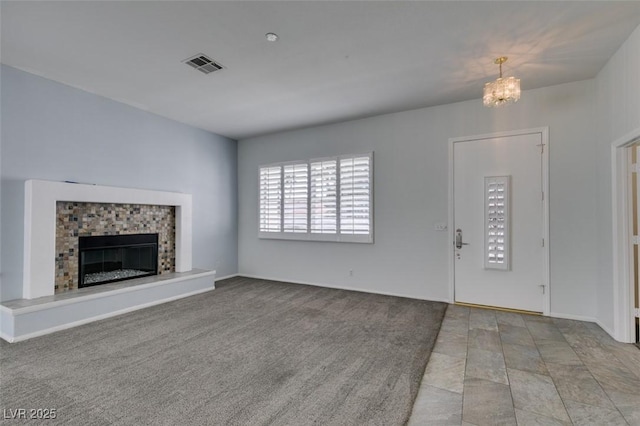 unfurnished living room featuring a chandelier, a glass covered fireplace, visible vents, and carpet flooring