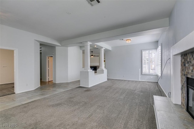 unfurnished living room with carpet floors, a fireplace with raised hearth, visible vents, and ornate columns