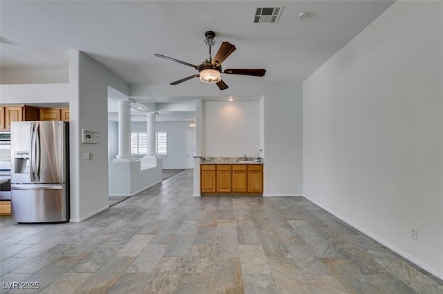 unfurnished living room featuring decorative columns, baseboards, visible vents, ceiling fan, and a sink