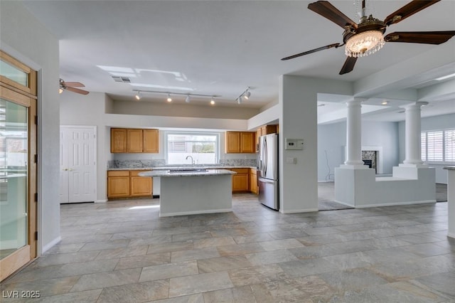 kitchen featuring a center island, decorative columns, stainless steel refrigerator with ice dispenser, open floor plan, and ceiling fan