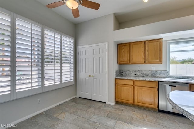 kitchen with light stone countertops, baseboards, stainless steel dishwasher, brown cabinets, and stone finish flooring