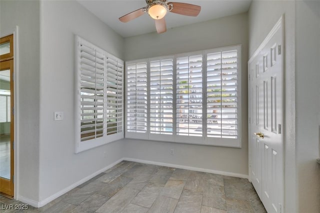 unfurnished room featuring a healthy amount of sunlight, stone finish flooring, and baseboards