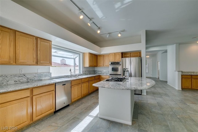 kitchen with a center island, a breakfast bar, appliances with stainless steel finishes, a sink, and light stone countertops