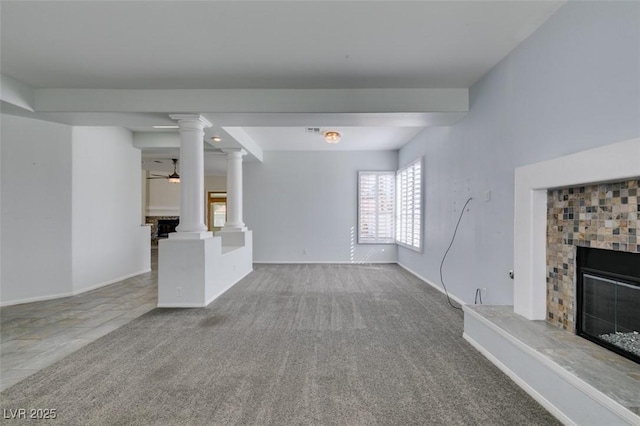 unfurnished living room featuring carpet floors, baseboards, a fireplace, and ornate columns