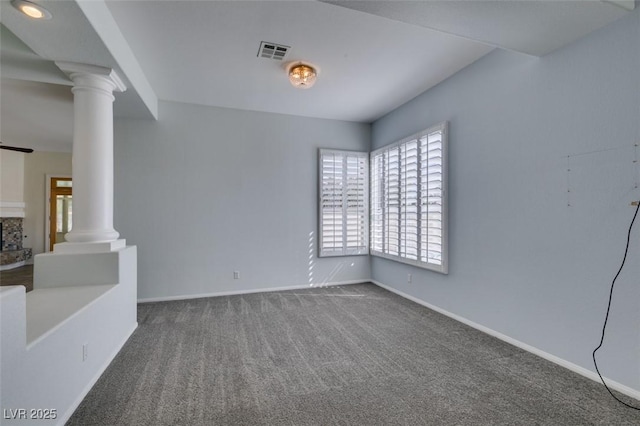 spare room featuring carpet floors, decorative columns, visible vents, and baseboards