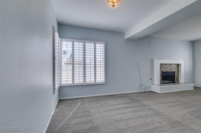 unfurnished living room featuring baseboards, carpet flooring, and a glass covered fireplace