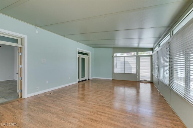 spare room with baseboards and wood finished floors