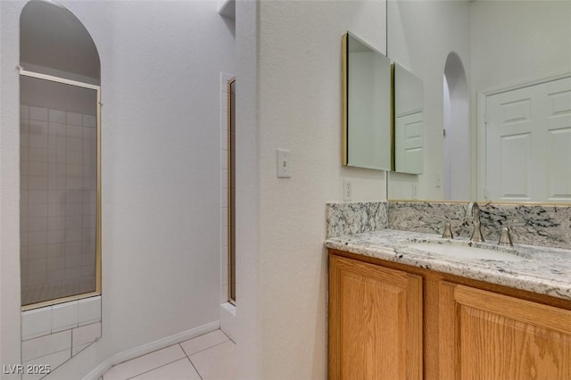 bathroom with baseboards, an enclosed shower, vanity, and tile patterned floors