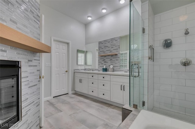 bathroom featuring double vanity, a shower stall, baseboards, and a sink