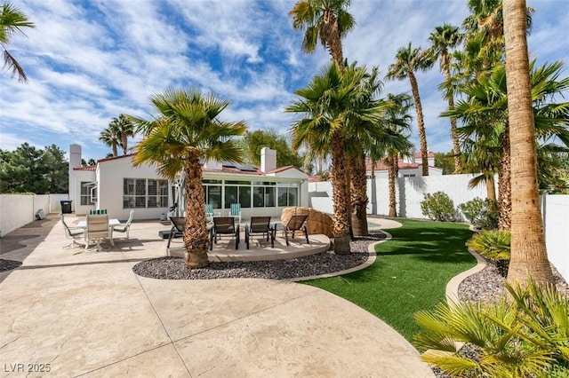 back of house with a yard, a patio, stucco siding, a sunroom, and a fenced backyard