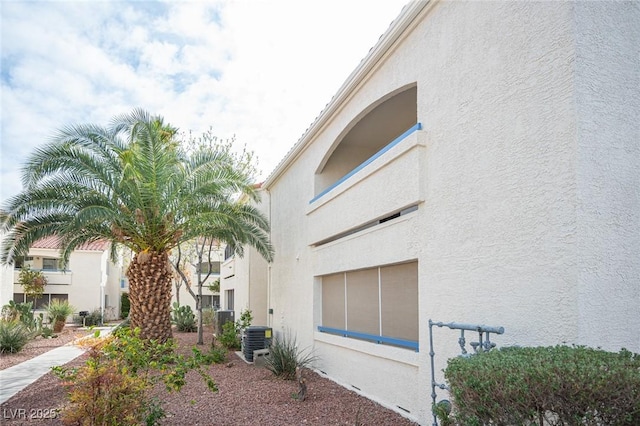 exterior space with cooling unit and stucco siding