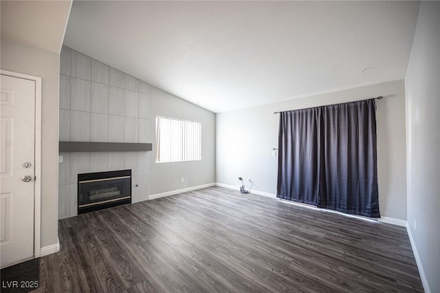 unfurnished living room featuring lofted ceiling, a large fireplace, dark wood-type flooring, and baseboards