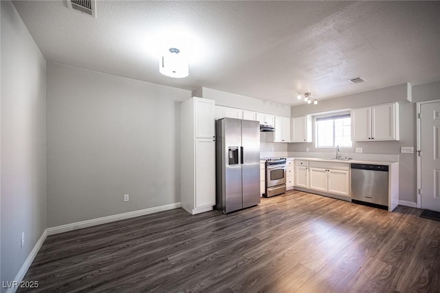 kitchen with a sink, visible vents, white cabinetry, appliances with stainless steel finishes, and dark wood-style floors