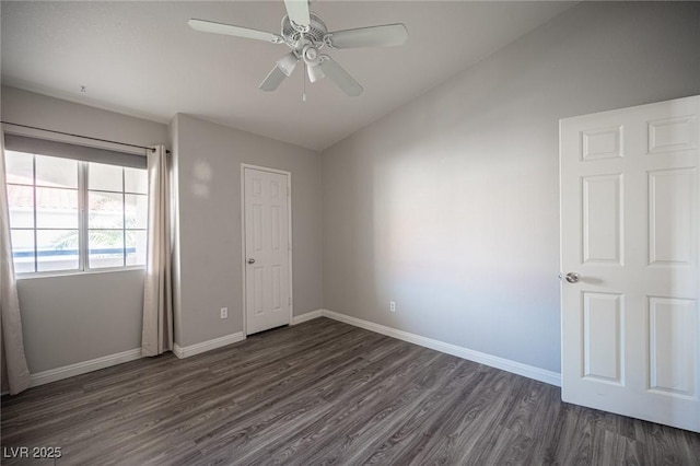 unfurnished bedroom with lofted ceiling, dark wood-style floors, a ceiling fan, and baseboards