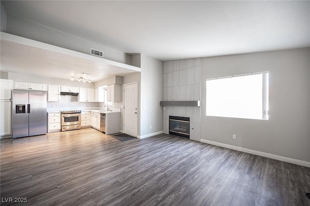 kitchen with a large fireplace, visible vents, baseboards, open floor plan, and appliances with stainless steel finishes