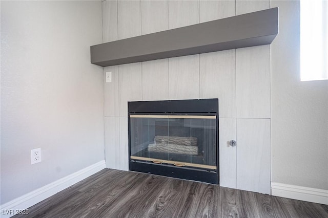 interior details with wood finished floors, a glass covered fireplace, and baseboards