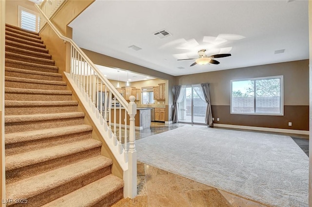 interior space with stairway, baseboards, visible vents, and ceiling fan