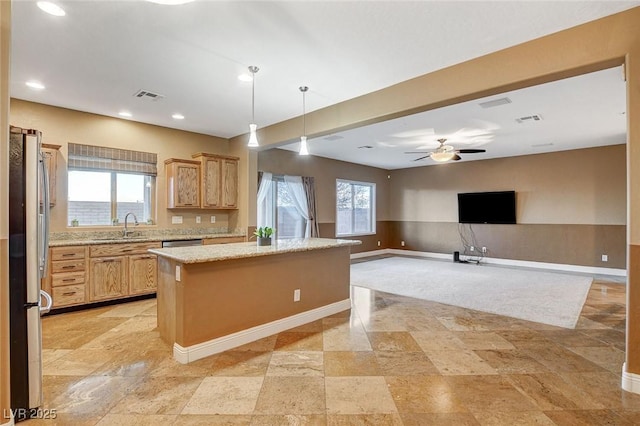 kitchen featuring visible vents, plenty of natural light, a kitchen island, and a sink