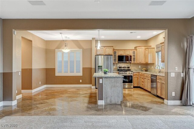 kitchen with a sink, decorative light fixtures, a center island, appliances with stainless steel finishes, and glass insert cabinets