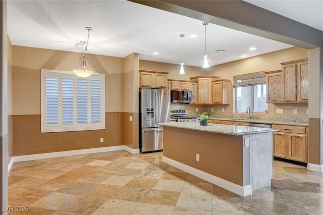 kitchen with a kitchen island, baseboards, light stone countertops, pendant lighting, and stainless steel appliances