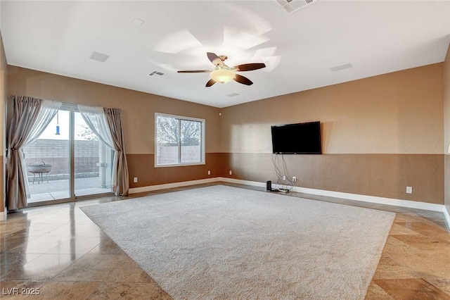 unfurnished living room with visible vents, wainscoting, baseboards, and ceiling fan