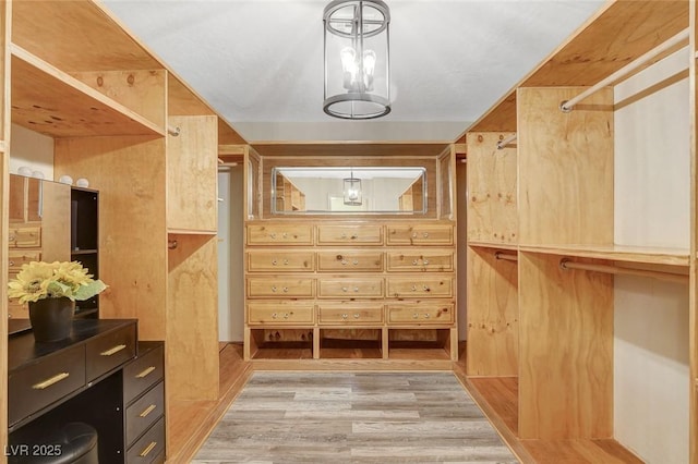 spacious closet with a notable chandelier and light wood-type flooring