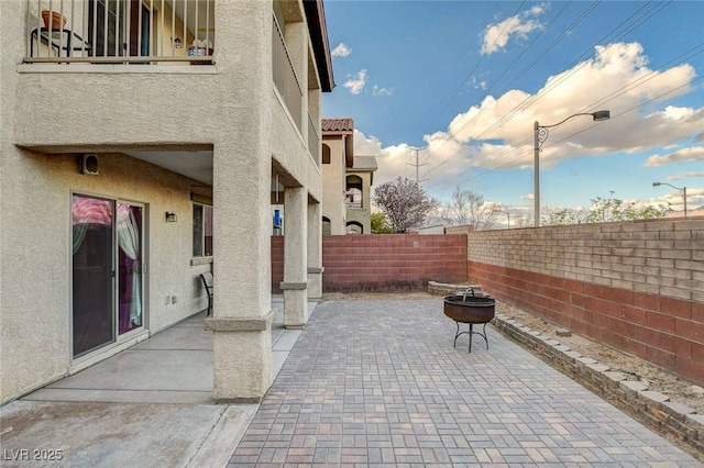 view of patio / terrace featuring a balcony, fence private yard, and an outdoor fire pit