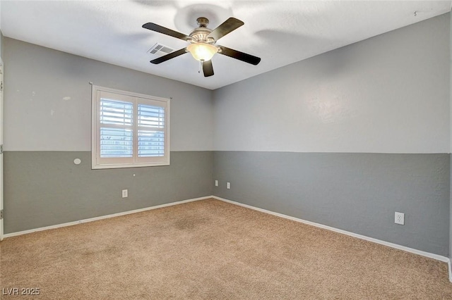 carpeted spare room with visible vents, baseboards, and ceiling fan