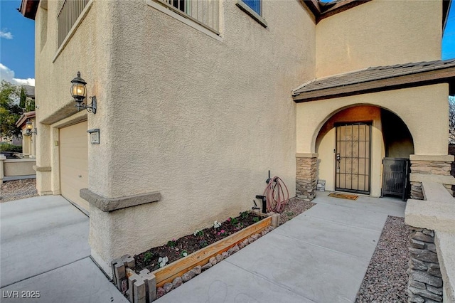 property entrance featuring stucco siding, stone siding, and an attached garage