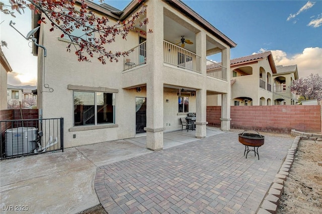 rear view of property with central air condition unit, stucco siding, and fence