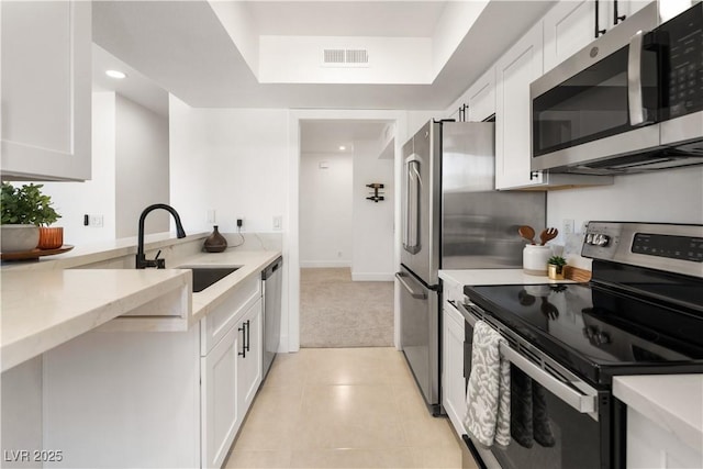 kitchen with light tile patterned floors, visible vents, appliances with stainless steel finishes, white cabinets, and a sink