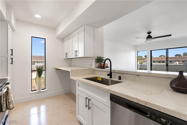 kitchen featuring a healthy amount of sunlight, light stone countertops, appliances with stainless steel finishes, and a sink