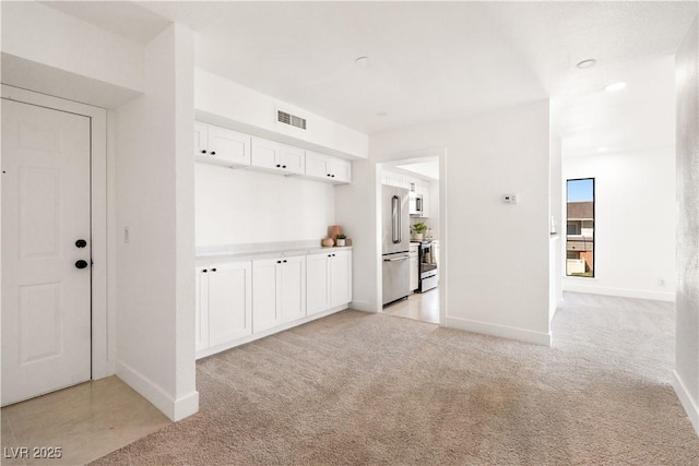 interior space with baseboards, visible vents, and light colored carpet