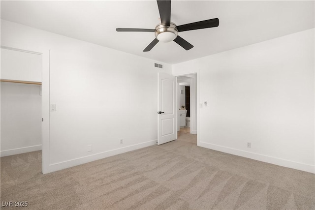 unfurnished bedroom with a walk in closet, visible vents, and light colored carpet