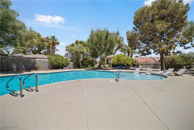 pool with a patio area and fence