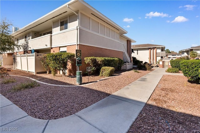 view of side of property featuring brick siding and fence