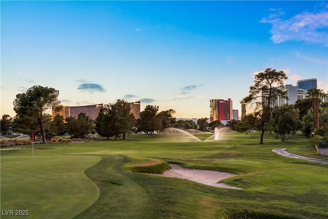 view of property's community with view of golf course and a yard