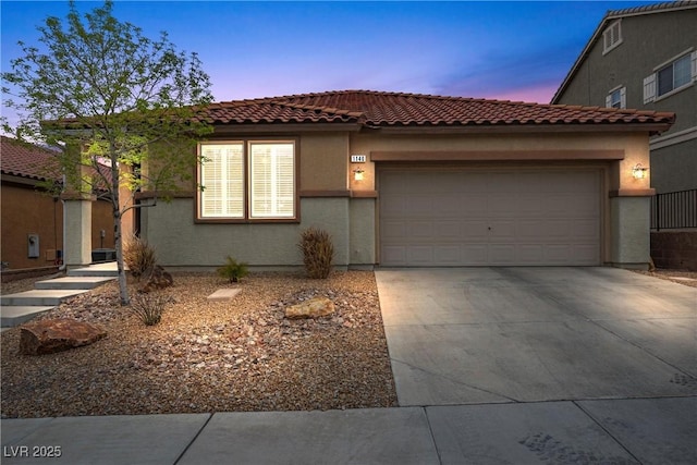 mediterranean / spanish-style home featuring a garage, concrete driveway, and stucco siding