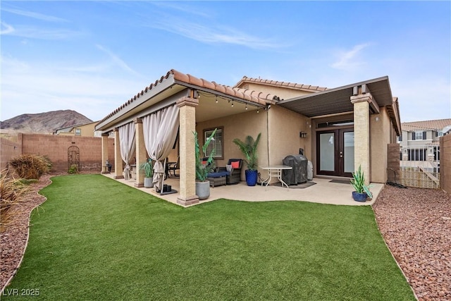 rear view of property with french doors, a yard, stucco siding, a patio area, and a fenced backyard