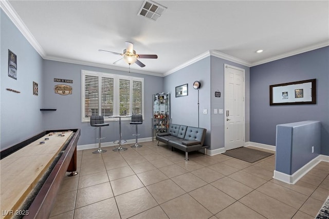 interior space with crown molding, light tile patterned floors, visible vents, a ceiling fan, and baseboards